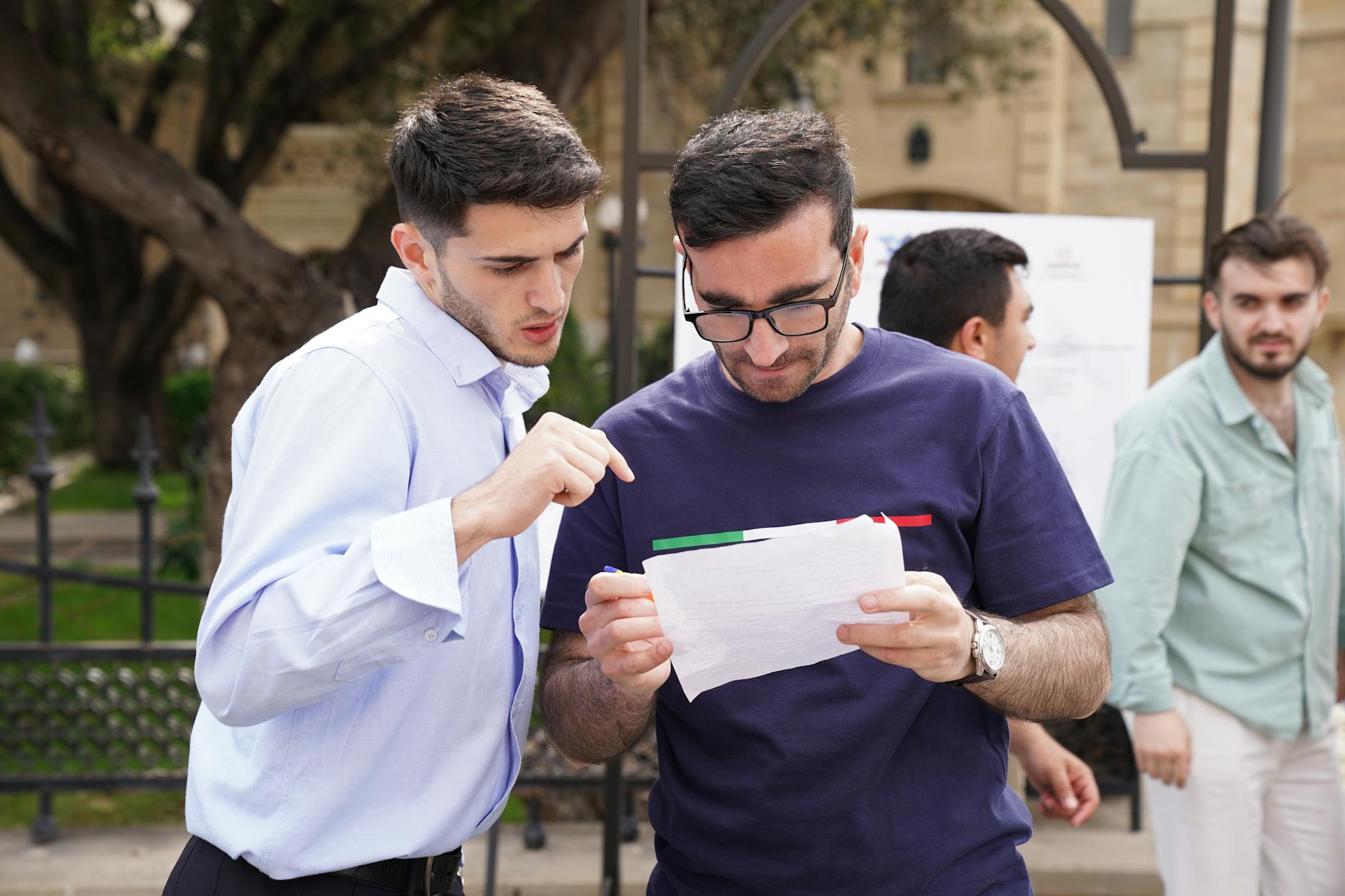 Grupa dorosłych analizuje wydruki i dyskutuje nad nimi w parku