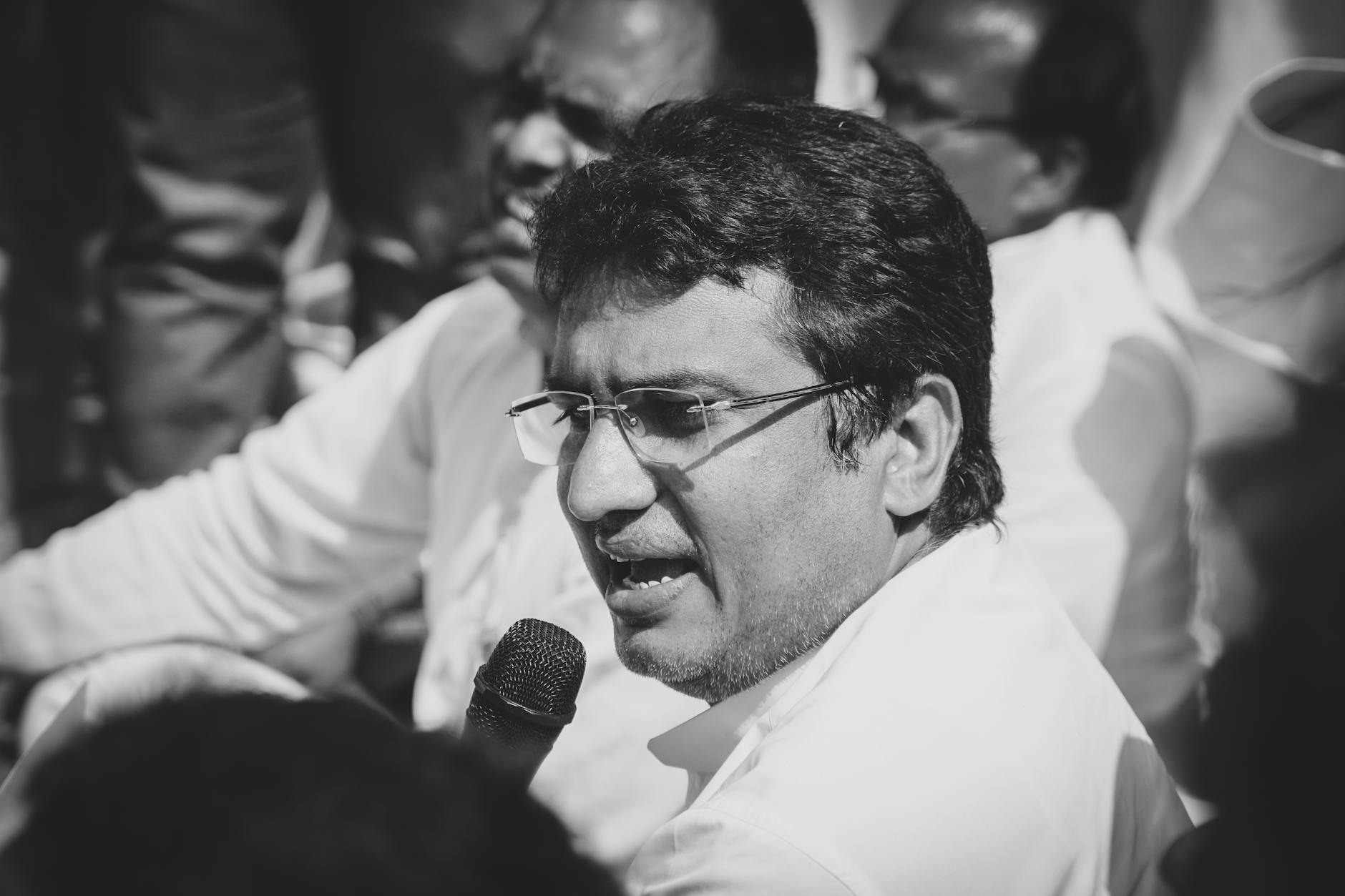 Moderator w okularach mówi do mikrofonu podczas spotkania fokusowego Moderator w okularach mówi do mikrofonu podczas spotkania fokusowego