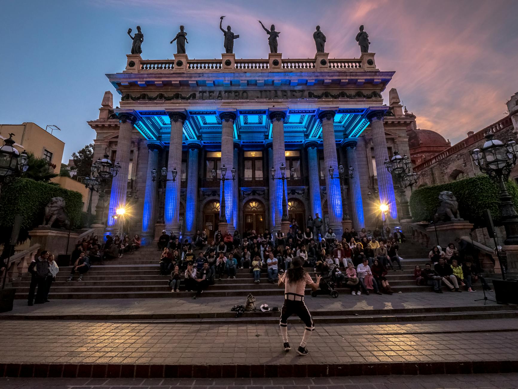 Uliczny artysta występuje przed tłumem przy Teatro Juárez o zachodzie słońca
