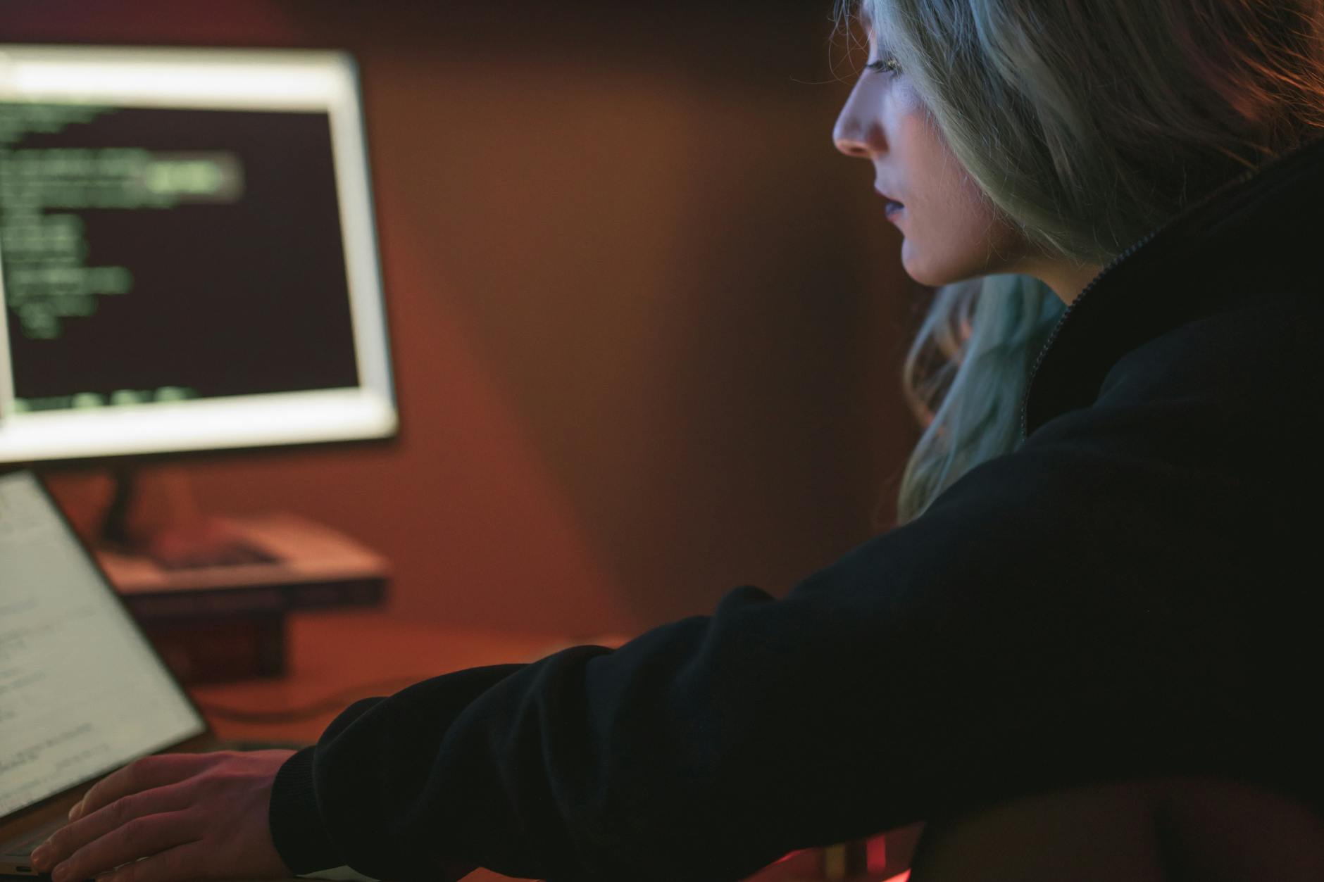 Programistka pracuje nocą przy laptopie z kodem w ciemnym pokoju Programistka pracuje nocą przy laptopie z kodem w ciemnym pokoju