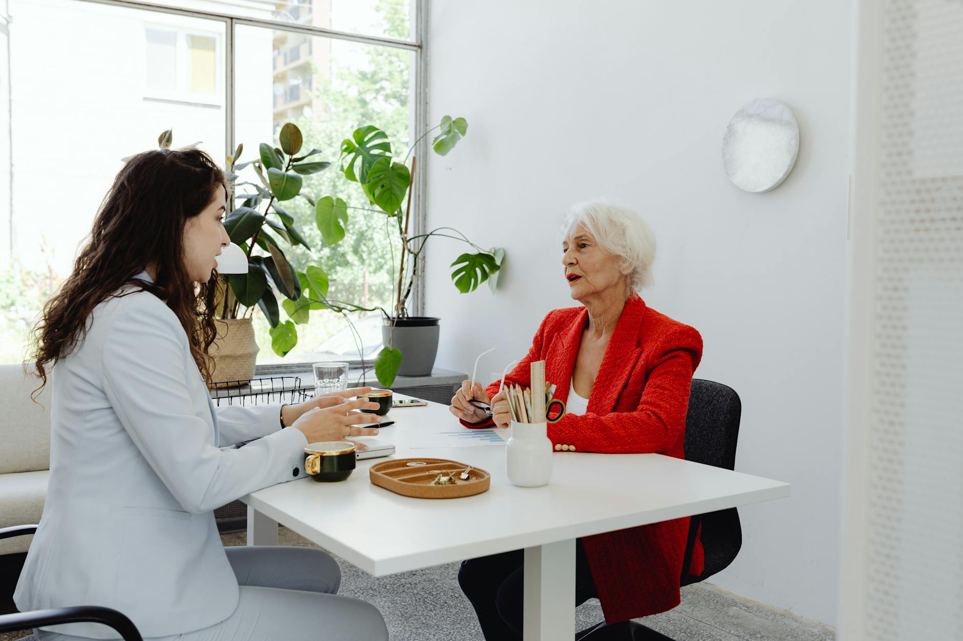 Dwie bizneswoman rozmawiają przy biurku w biurze z roślinami