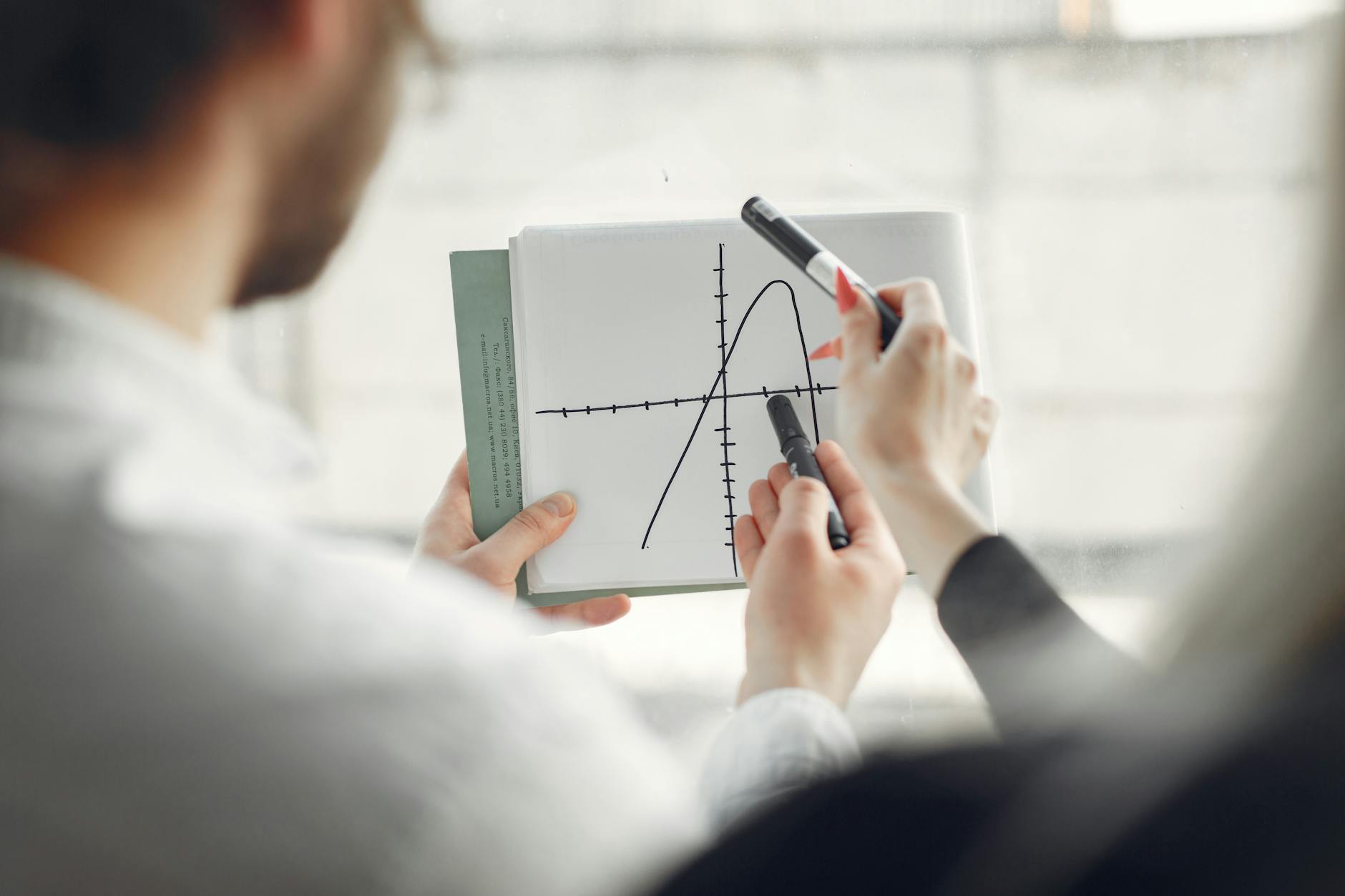 Dwoje analityków omawia wykres krzywej w notesie podczas pracy