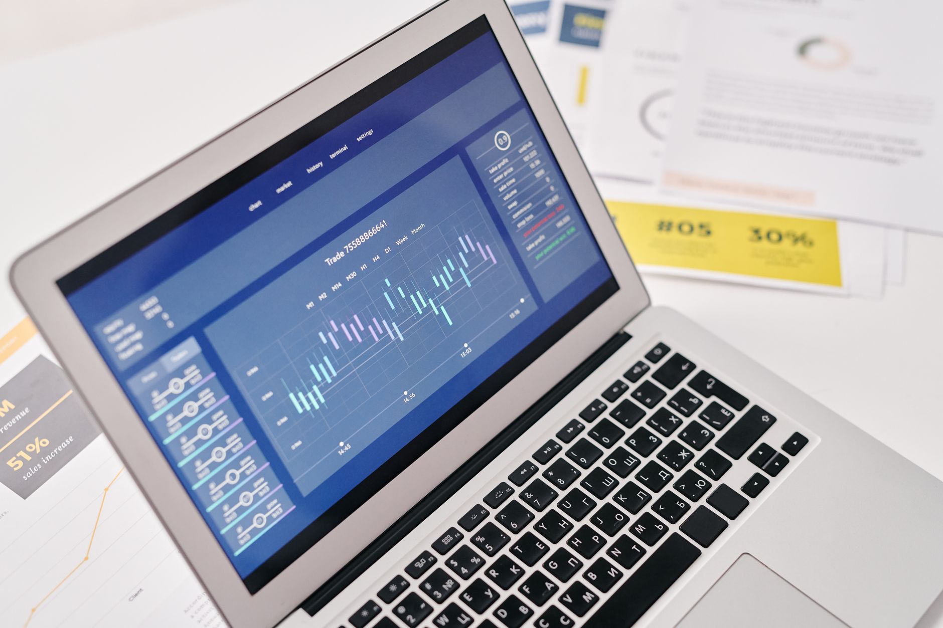 Laptop z wykresami finansowymi i dokumentami na biurku