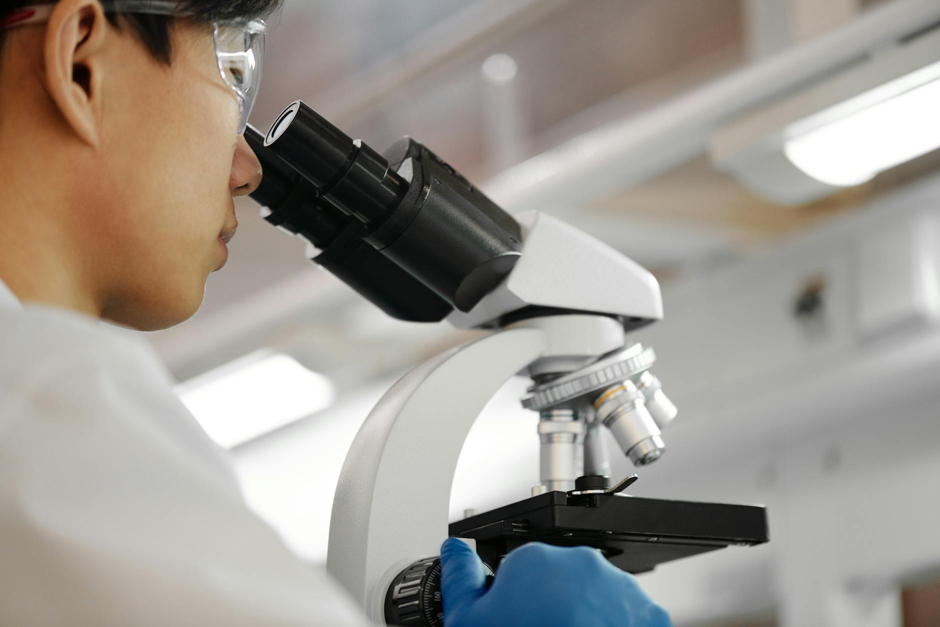 Naukowiec pochylony nad mikroskopem w nowoczesnym laboratorium
