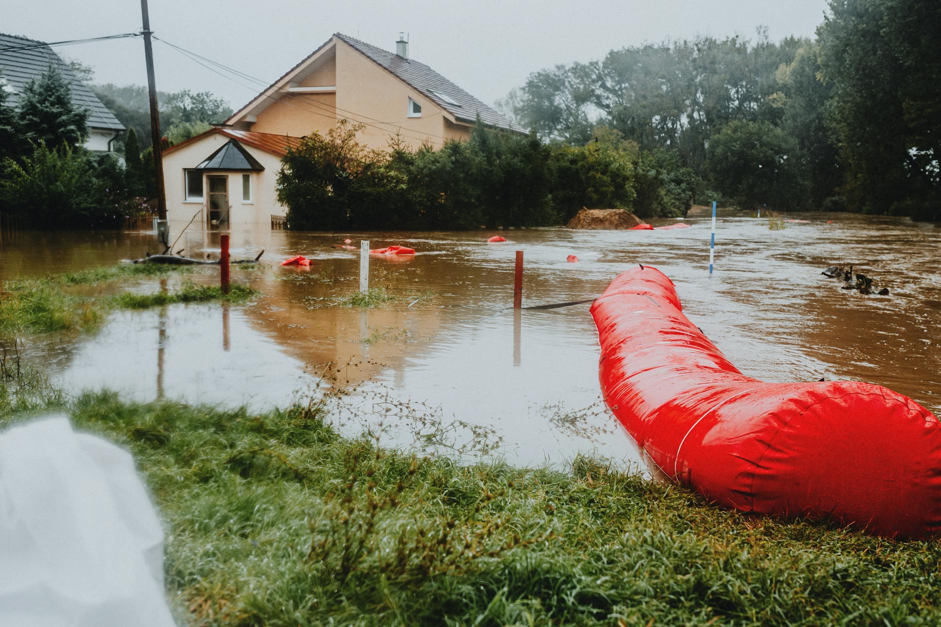 Zalane osiedle mieszkaniowe zabezpieczone czerwonymi zaporami przeciwpowodziowym