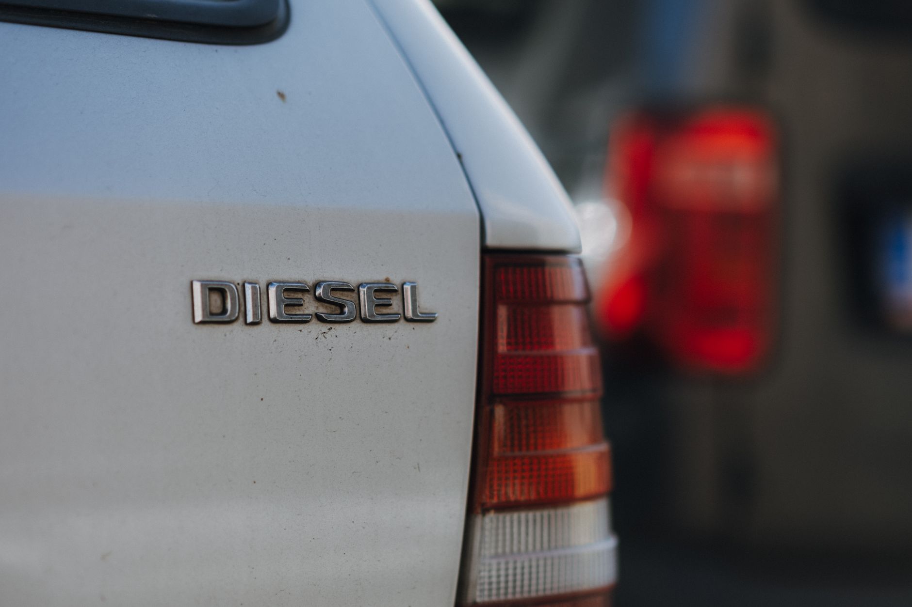 Zbliżenie na emblemat samochodu z napisem diesel na tle miasta