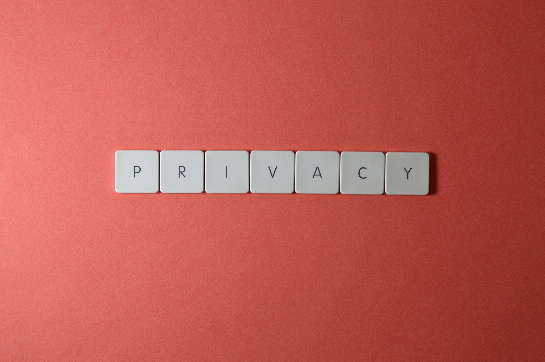 Kafelkowe litery układające się w słowo privacy na czerwonym tle